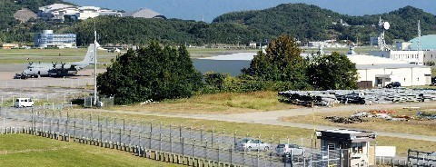 米軍輸送機（左端）の飛来時に福岡空港の国際線ターミナル付近から撮影した米軍専用区域。目隠しのように立ち並ぶ樹木の向こうにあるのが「米空軍航空機動軍団」の建物だ＝2014年10月15日、福岡市博多区