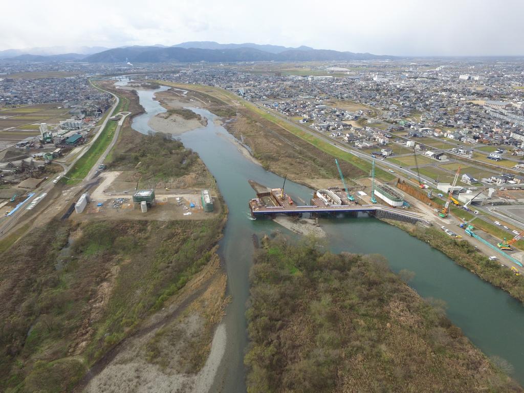 北陸新幹線　金沢－敦賀延伸　新九頭竜橋（仮称進捗状況　【写真】 2016年12月中旬 （左上） 写真1.橋りょう工事の全景状況（写真の手前が九頭竜川の上流になります）