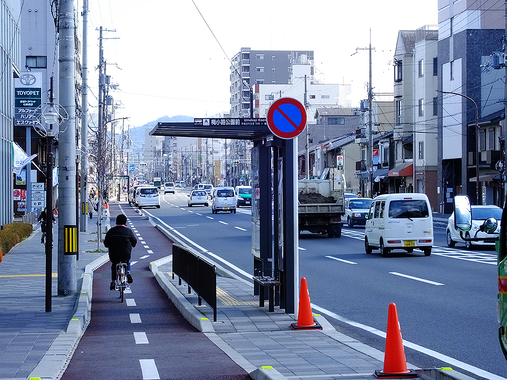 七条通と山陰線の交差ポイントを背にし、七条通東方（鴨川方）を見る。この通りには、京都駅と洛西・北大路を結ぶ京都市バスなどが走っている