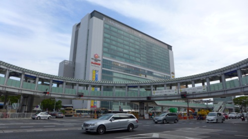 円形の歩道橋が駅前を通る横浜市道環状2号線をまたぎ、駅ビルがそびえたつJR新横浜駅